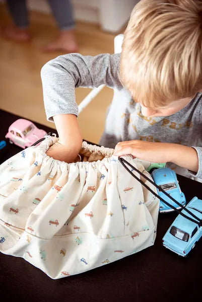 Mini sac de rangement et tapis de jeux motif voitures de Playandgo - vue du sac ouvert avec un enfant qui plonge sa main dedans