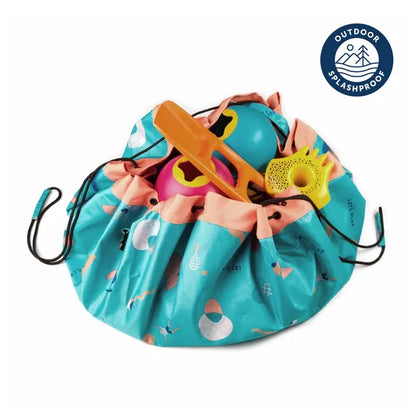 Tapis de jeu et sac de rangement d’extérieur Play and Go – motif jeux – vue du sac en version rangement avec des jouets à l’intérieur – écusson “outdoor splashproof” visible sur la photo