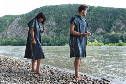Poncho-serviette unisexe de Cocoon - vue de profil, porté par un homme et par une femme devant un lac